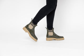 Lemon Jelly, Flow, Military Green patent ankle boot with tan elastic sides and big thick tan tread styled with black jeans and modelled with feet and legs, The Shoe Curator