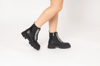 Gioseppo, Holzthum, Black patent ary boots with high and thick tread and think laces down the front with big chains modelled with feet and legs, The Shoe Curator