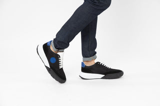 Ted Bake, Areli, Black and white sneaker with white laced and white sole with blue detailing at the front and back modelled with feet and legs, The Shoe Curator