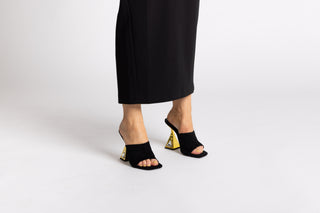 Kat Maconie black suede leather mule heel, open toe. Gold heels stacked on a crystal gem in the heel with legs and long black skirt