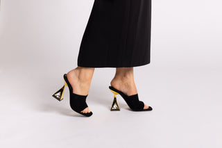 Kat Maconie black suede leather mule heel, open toe. Gold heels stacked on a crystal gem in the heel with legs and long black skirt