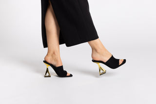 Kat Maconie black suede leather mule heel, open toe. Gold heels stacked on a crystal gem in the heel with legs and long black skirt