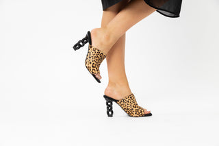 Kat Maconie, Kylie, Leopard print suede peeped toe high heel with a black link chain heel styled with a long black dress and modelled with feet and legs, The Shoe Curator