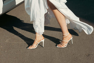 Billini, Preach, White leather strappy with with small silver buckle and pointed toes with stiletto heel styled with white dress modelled with feet and legs, The Shoe Curator