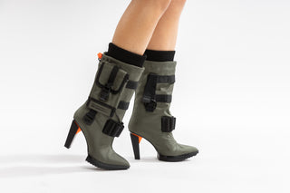 United Nude, Pocket Lev, mid calf pointed toe boots with functional pockets, utility straps and detachable nylon accessories and a block heel with orange detailing modelled with feet and legs, The Shoe Curator