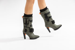 United Nude, Pocket Lev, mid calf pointed toe boots with functional pockets, utility straps and detachable nylon accessories and a block heel with orange detailing modelled with feet and legs, The Shoe Curator