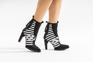 United Nude, Lev Calli Hi, Black and white leather boot with stripes in the middle and black on the front and back with zip, floating small block heel floating modelled with feet and legs, The Shoe Curator