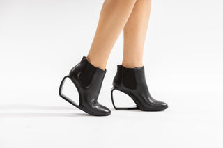 United Nude, Step Mobius Chelsea, Black leather ankle cut boot with elastic sides and a single strand heel with a middle opening modelled with feet and legs, The Shoe Curator