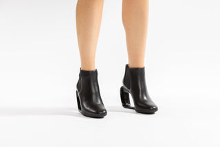 United Nude, Step Mobius Chelsea, Black leather ankle cut boot with elastic sides and a single strand heel with a middle opening modelled with legs and feet, The Shoe Curator