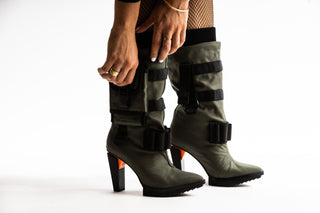 United Nude, Pocket Lev, mid calf pointed toe boots with functional pockets, utility straps and detachable nylon accessories and a block heel with orange detailing styled with sheer stockings and modelled with legs, feet and hands, The Shoe Curator