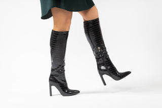 Billini, Rasana, Black croc patent knee high bool with slim wide block with pointed toes styled with green dress and modelled with feet and legs, The Shoe Curator