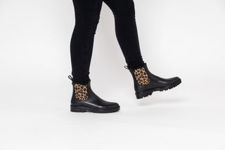 Verbenas, Gaudi, Black patent ankle boot with black animal print elastic sides and big thick black tread styled with black jeans modelled with feet and legs, The Shoe Curator