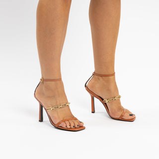 Kat Maconie, Arboga-Caramel, thing leather caramel strap with gold chain strap and stiletto heel modelled with feet and legs, The Shoe Curator