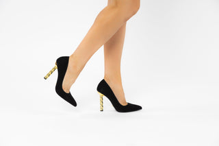 Kat Maconie, Lydia, Black suede stiletto with pointed toes and a twisted gold chain heel modelled with feet and legs, The Shoe Curator