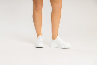 Casadei, Salen, White leather sneakers with white laces and a thick heel and sole with casadei on the back modelled with feet and legs, The Shoe Curator