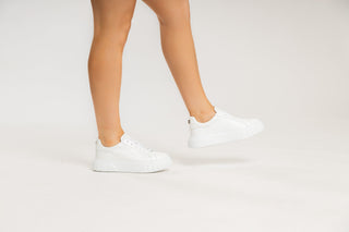 Casadei, Salen, White leather sneakers with white laces and a thick heel and sole with casadei on the back modelled with feet and legs, The Shoe Curator