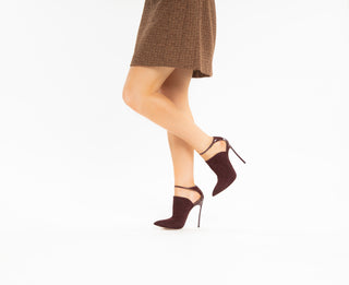 Casadei, Scarpa Camoscio, Red suede ankle high boots with thin adjustable straps and pointed covered toes with thin heel styled with brown skirt and modelled with feet and legs, The Shoe Curator