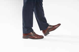 Fluchos, Chris, Brown leather shoes with pointed toe and stiching patterns on the front with brown laces modelled with feet and legs, The Shoe Curator
