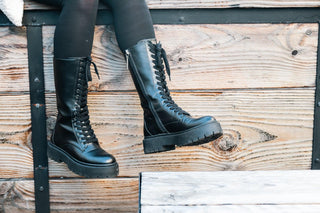 Gioseppo, Kitui, Black leather mid-calf boots with laces up the front and thick black rubber sole styled with thick sheer rights and modelled with feet and legs, The Shoe Curator