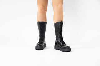 Gioseppo, Kitui, Black leather mid-calf boots with laces up the front and thick black rubber sole modelled with feet and legs, The Shoe Curator