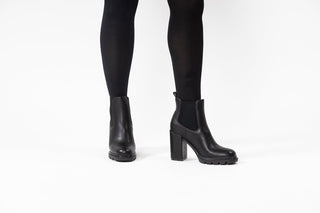 Gioseppo,Tindouf, Black leather ankle boot with elastic chunk and block heel with black rubber sole styled with black sheer pants and modelled with legs and feet, The Shoe Curator