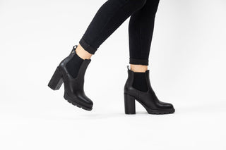 Gioseppo,Tindouf, Black leather ankle boot with elastic chunk and block heel with black rubber sole styled with black jeans and modelled with legs and feet, The Shoe Curator