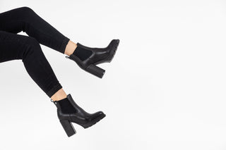 Gioseppo,Tindouf, Black leather ankle boot with elastic chunk and block heel with black rubber sole styled with black jeans and modelled with feet and legs, The Shoe Curator