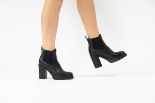 Gioseppo,Tindouf, Black leather ankle boot with elastic chunk and block heel with black rubber sole modelled with feet and legs, The Shoe Curator