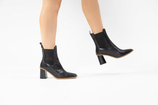 Gioseppo, Yala, Black leather ankle boot with pointed toes and brown rubber sole with elastic chunk and sharp edged block heel modelled with feet and legs, The Shoe Curator