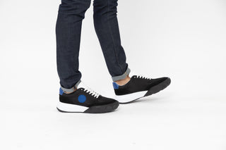 Ted Bake, Areli, Black and white sneaker with white laced and white sole with blue detailing at the front and back modelled with feet and legs, The Shoe Curator