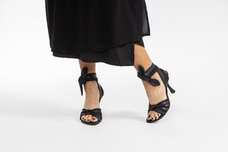 Ted Baker, Ezrayah, Black leather stiletto with 3 ties coming into a knot with peeped toes and a wrap around the ankle styled with dress and modelled with feet and legs, The Shoe Curator