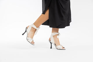 Ted Baker, Ezrayah, White leather pump with ties in a knot on the front of the peeped toes and with wrap around the ankle styled with black dress and modelled with feet and legs, The Shoe Curator