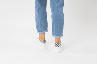Ted Baker, Filona, White sneakers with blue checker pattern on the heel styled with jeans and modelled with feet and legs, The Shoe Curator