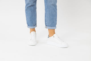 Ted Baker, Filona, White sneakers with blue checker pattern on the heel styled with jeans and modelled with feet and legs, The Shoe Curator