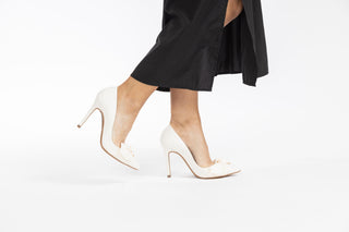 Ted Baker, Hyana, White leather stiletto with pointed toes and bow on the front styled with dress and modelled with feet and legs, The Shoe Curator