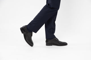 Ted Baker, Kampten, Black leather dinner shoes with pointed toes and black laces styled with dress pants and modelled with feet and legs, The Shoe Curator