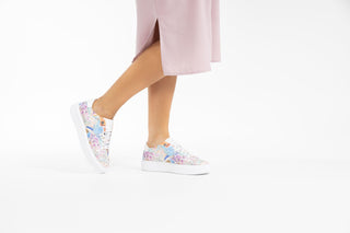 Ted Baker, Lorma, White sneakers with light floral designs with white laces styled with pink dress and modelled with feet and legs, The Shoe Curator