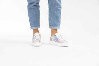 Ted Baker, Lorma, White sneakers with light floral designs with white laces styled with jeans and modelled with feet and legs, The Shoe Curator