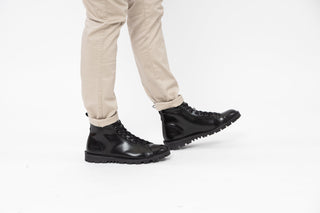 Ted Baker, Yousi, Black leather ankle boots with laces and black bumpy sole tread styled with pants and modelled with feet and legs, The Shoe Curator