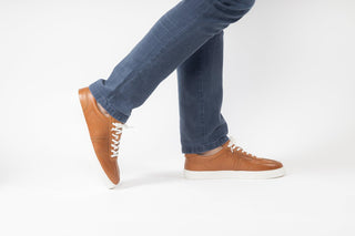 Ted Baker, Robertt, Tan leather sneakers with white soles and laces styled with jeans and modelled with feet and legs, The Shoe Curator